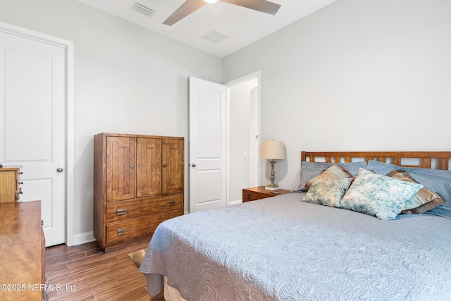 bedroom with a ceiling fan, baseboards, visible vents, and wood finished floors