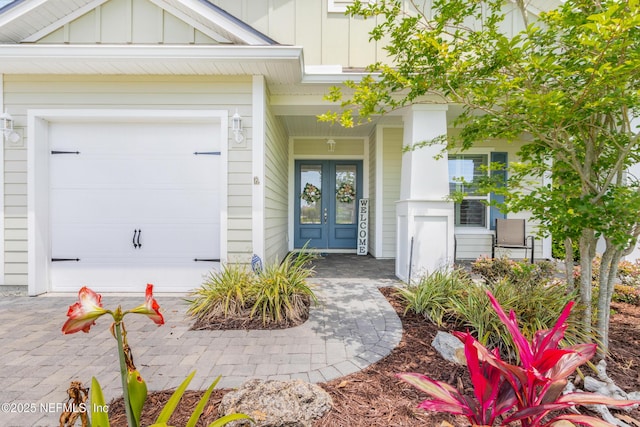 view of exterior entry featuring a garage, french doors, and board and batten siding