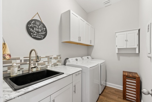 laundry area with dark wood finished floors, cabinet space, visible vents, a sink, and washer and dryer