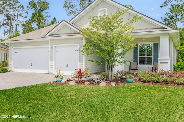 craftsman-style house featuring board and batten siding, a front yard, driveway, and an attached garage