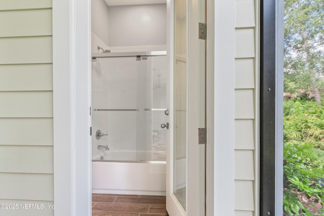 full bathroom with combined bath / shower with glass door and wood finish floors