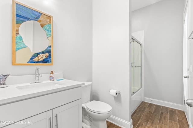 bathroom with bath / shower combo with glass door, toilet, wood tiled floor, vanity, and baseboards