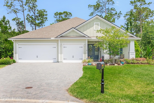 craftsman-style home featuring an attached garage, decorative driveway, french doors, board and batten siding, and a front yard