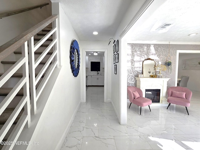 corridor with ornamental molding and a textured ceiling