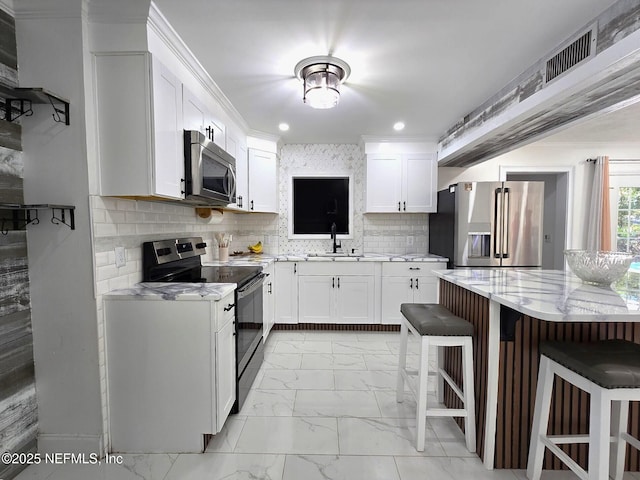 kitchen with light stone counters, stainless steel appliances, a breakfast bar area, and white cabinets