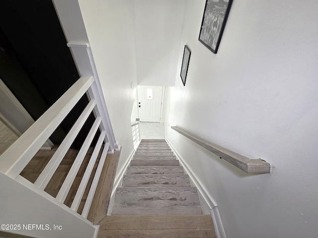 staircase featuring wood-type flooring and a high ceiling