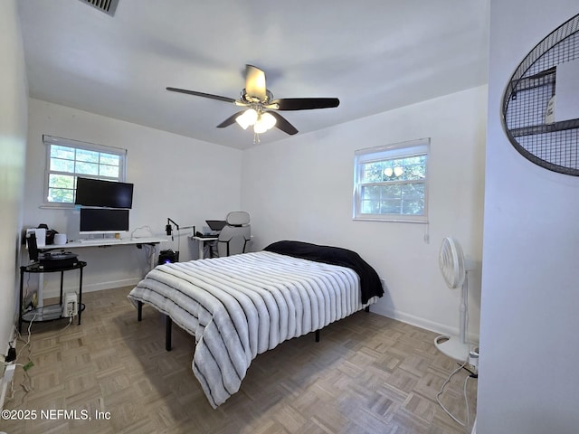 bedroom with multiple windows, ceiling fan, and light parquet flooring