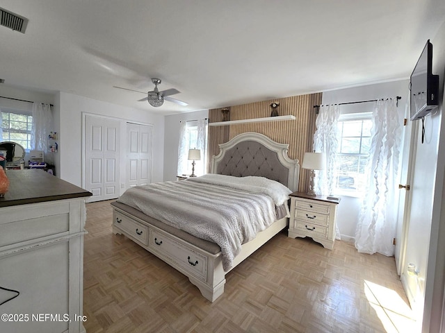 bedroom with multiple windows, ceiling fan, a closet, and light parquet floors