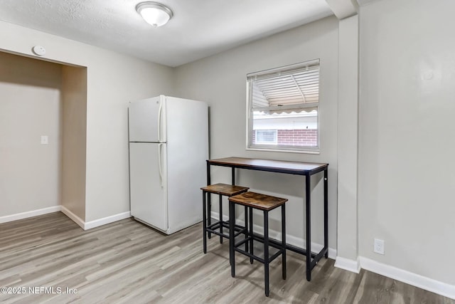 kitchen with light wood-type flooring, a kitchen breakfast bar, and white fridge