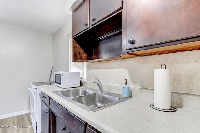 kitchen with white appliances, light hardwood / wood-style floors, dark brown cabinetry, and sink