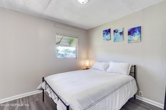 bedroom with dark hardwood / wood-style floors and a textured ceiling