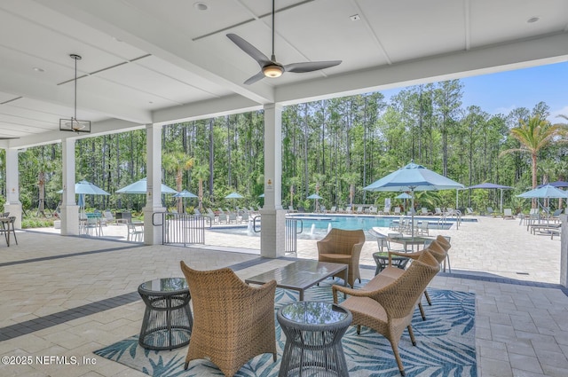 view of patio with a community pool and ceiling fan