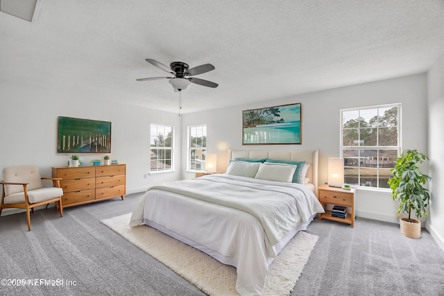 bedroom featuring multiple windows, ceiling fan, light colored carpet, and a textured ceiling