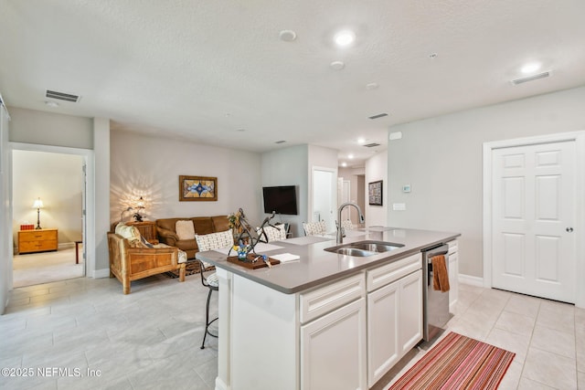 kitchen with light tile patterned floors, white cabinetry, a center island with sink, stainless steel dishwasher, and sink