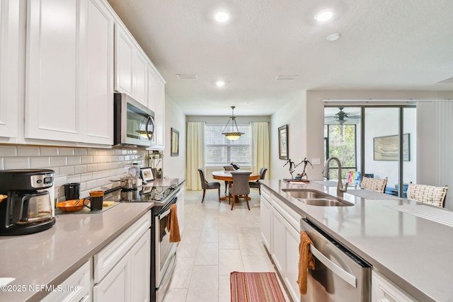 kitchen with white cabinetry, stainless steel appliances, tasteful backsplash, sink, and hanging light fixtures