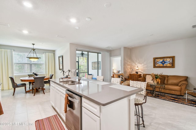 kitchen with pendant lighting, white cabinets, dishwasher, sink, and a center island with sink