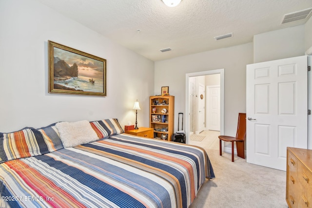 carpeted bedroom featuring ensuite bath and a textured ceiling