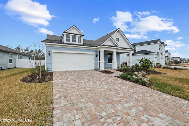 view of front of home with a garage, covered porch, and a front yard