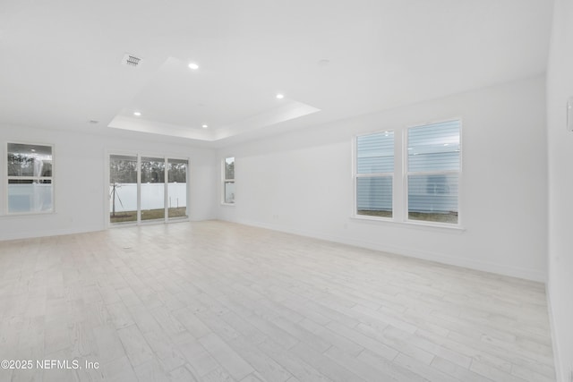 unfurnished room featuring a tray ceiling and light hardwood / wood-style floors