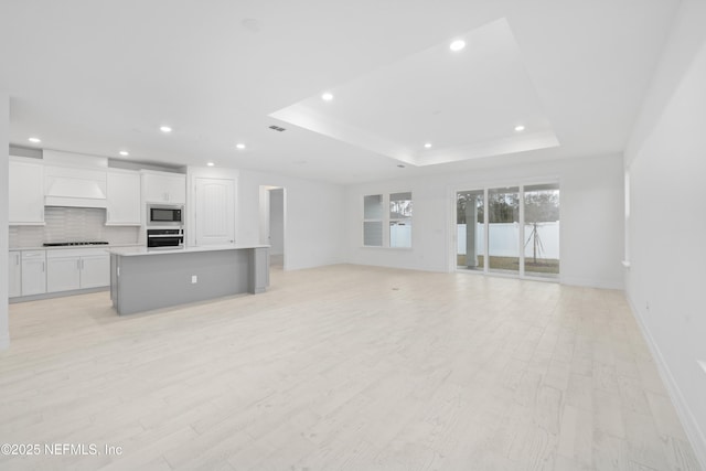 unfurnished living room with a raised ceiling and light hardwood / wood-style flooring