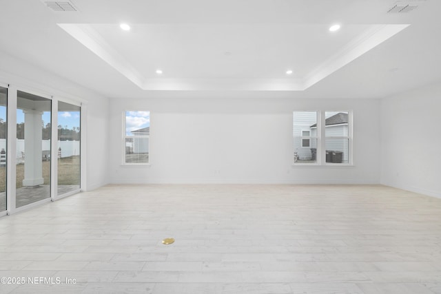 unfurnished room featuring crown molding, a raised ceiling, and light wood-type flooring