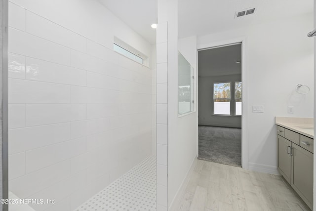 bathroom featuring tiled shower, vanity, and hardwood / wood-style floors