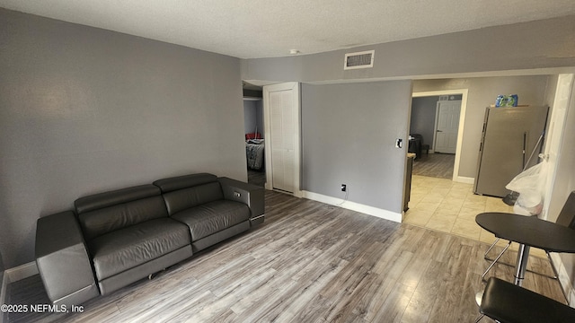 living room with a textured ceiling and light hardwood / wood-style floors