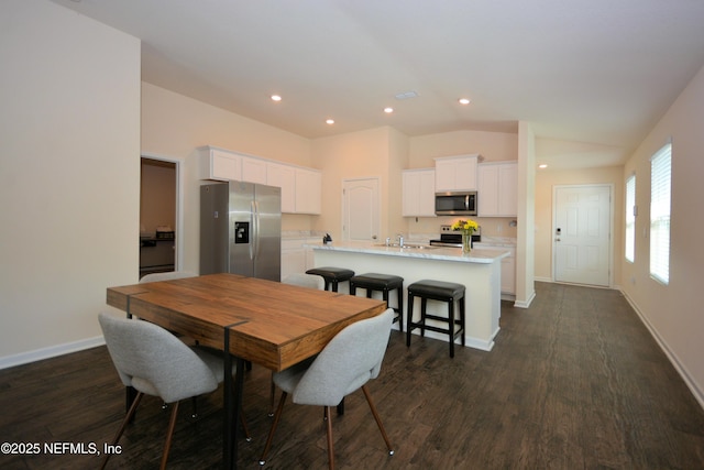 dining space featuring lofted ceiling, sink, and dark hardwood / wood-style floors