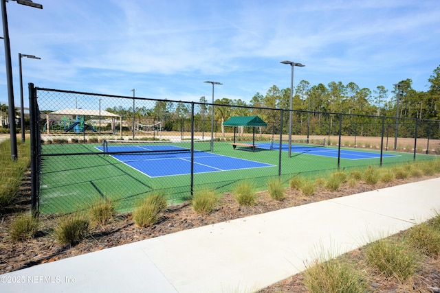 view of tennis court featuring a playground