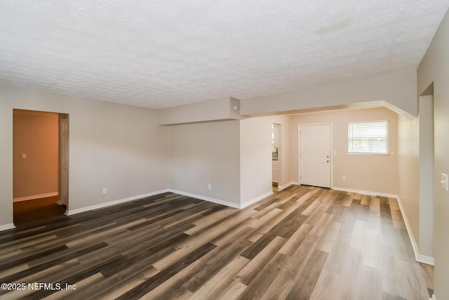 spare room with a textured ceiling and dark hardwood / wood-style flooring