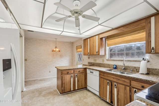 kitchen with sink, white appliances, a healthy amount of sunlight, decorative light fixtures, and kitchen peninsula