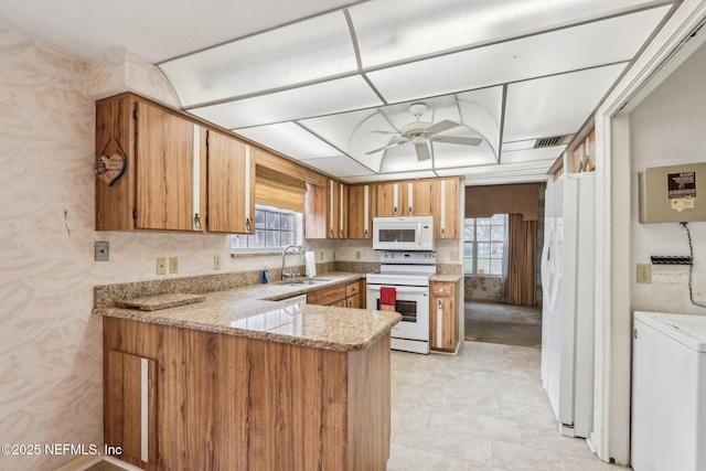 kitchen with sink, white appliances, kitchen peninsula, and a healthy amount of sunlight