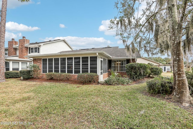 rear view of property featuring a yard and a sunroom