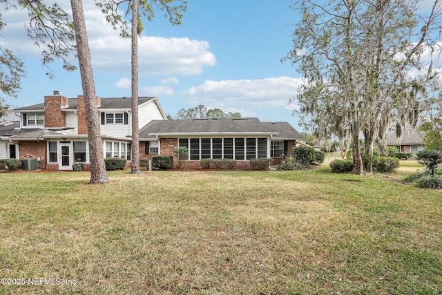 back of property with a sunroom, a lawn, and central air condition unit