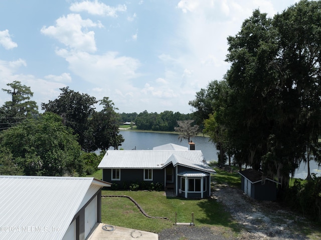 view of front facade with a front yard, a water view, and an outdoor structure