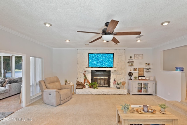 carpeted living room with ceiling fan, a textured ceiling, crown molding, and a fireplace