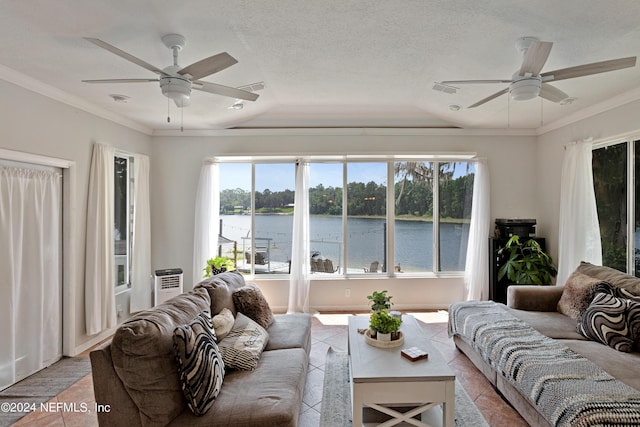 living room with ceiling fan, a textured ceiling, ornamental molding, and a water view