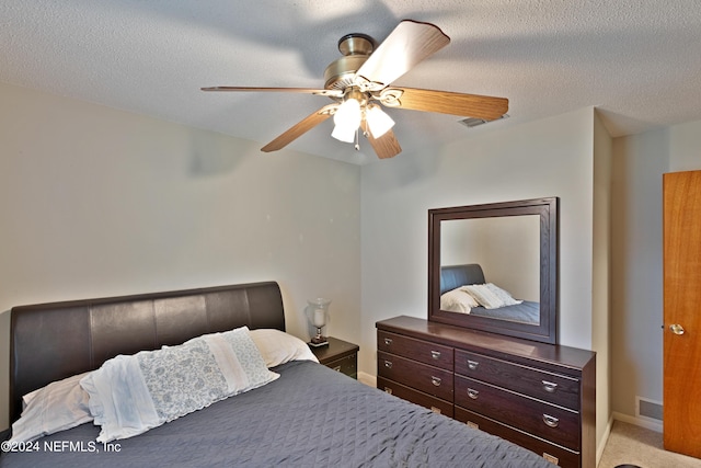 bedroom with ceiling fan, light colored carpet, and a textured ceiling