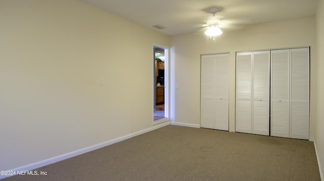 unfurnished bedroom featuring ceiling fan, carpet floors, and two closets