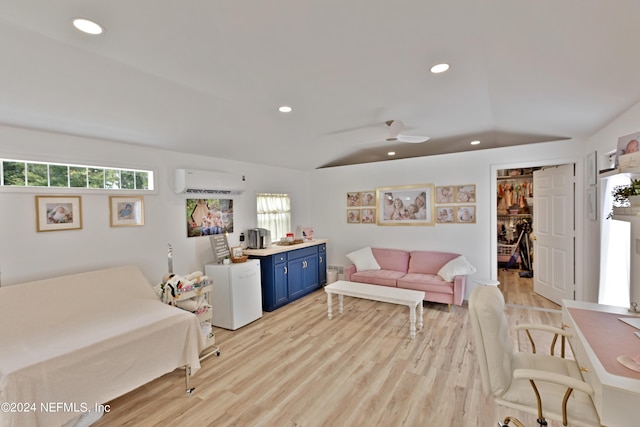 bedroom with a walk in closet, a closet, a wall unit AC, vaulted ceiling, and light hardwood / wood-style flooring