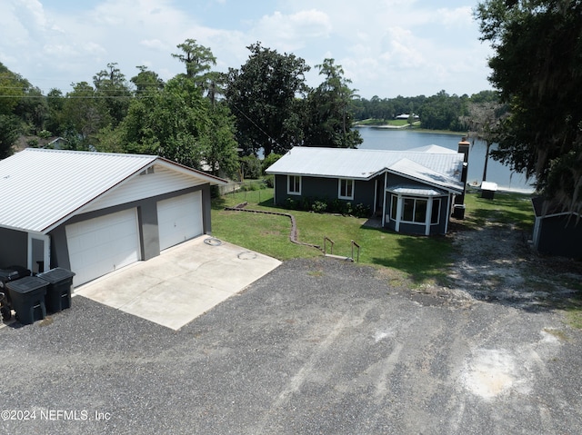 view of front facade with a front lawn, a garage, a sunroom, and a water view