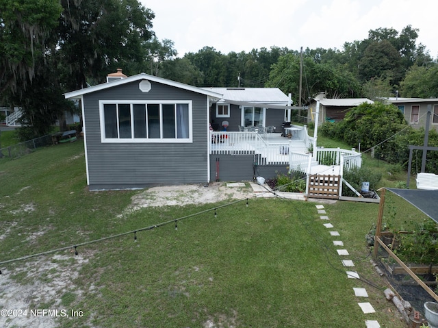 rear view of house with a deck and a yard