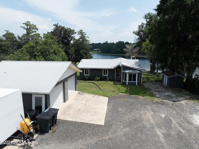 exterior space with a garage, an outbuilding, a lawn, and a water view