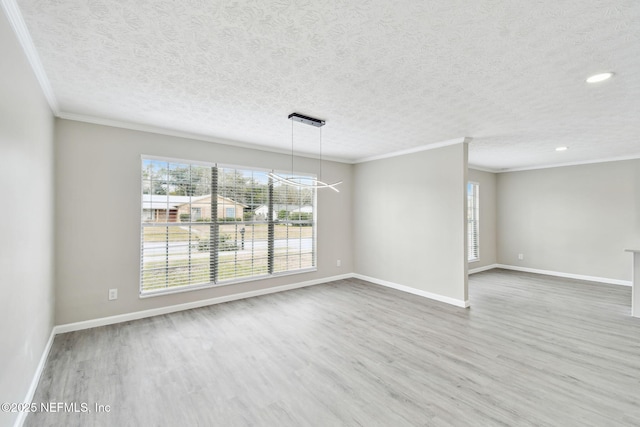 unfurnished room featuring ornamental molding, a textured ceiling, baseboards, and wood finished floors