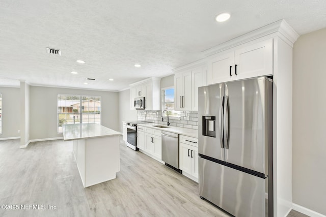 kitchen with light countertops, backsplash, appliances with stainless steel finishes, and a sink