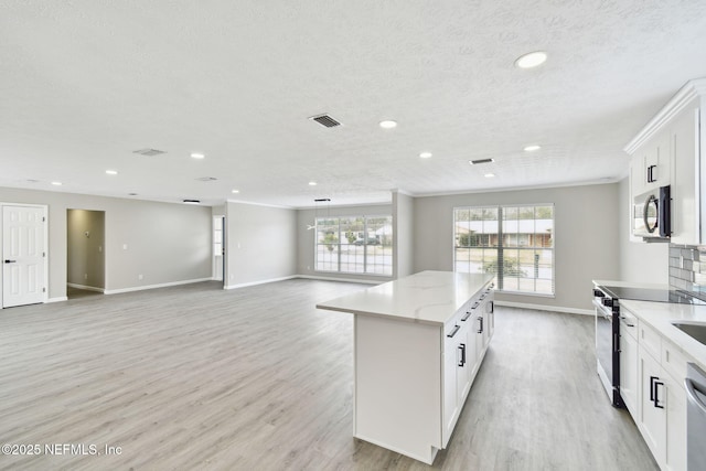 kitchen featuring visible vents, a center island, light wood-type flooring, appliances with stainless steel finishes, and white cabinetry