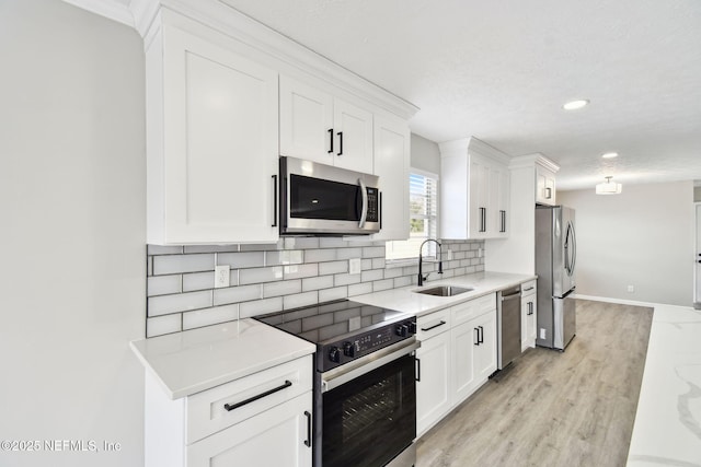 kitchen with white cabinets, tasteful backsplash, appliances with stainless steel finishes, and a sink