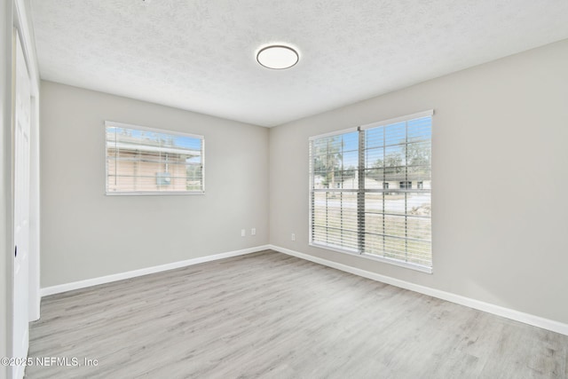 unfurnished room with baseboards, a textured ceiling, and wood finished floors