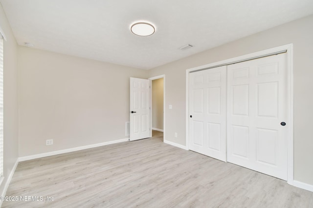 unfurnished bedroom featuring wood finished floors, baseboards, and a closet