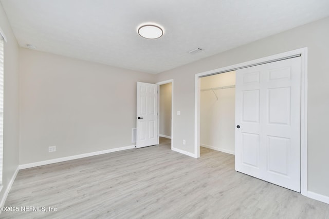 unfurnished bedroom featuring a closet, baseboards, and wood finished floors